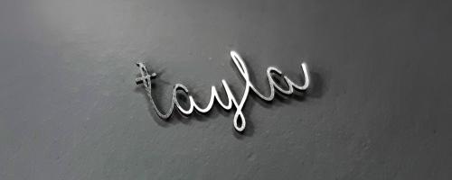 Laser-cutting of the name "Tayla" in metal in a handwritten style, used in jewelry personalization