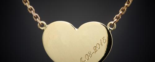 Gold heart-shaped charm engraved with a date, shown on a chain for jewelry customization